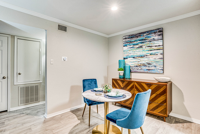 Elegant dining space with modern decor, featuring a chic marble table and vibrant blue chairs, complemented by contemporary artwork.