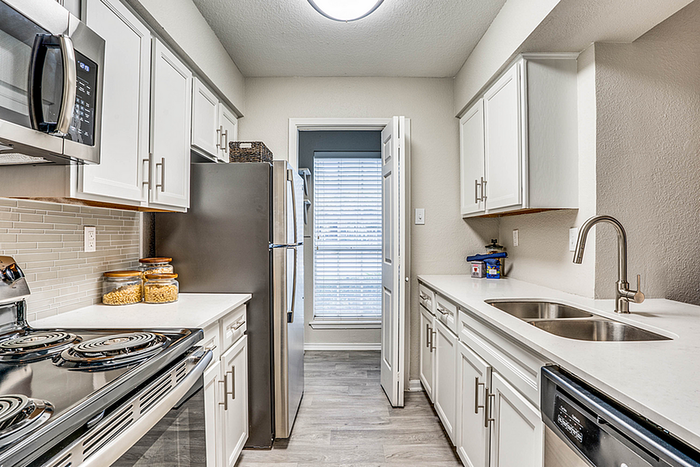 Modern kitchen with sleek stainless steel appliances, elegant white cabinetry, and spacious countertops offering style and functionality.