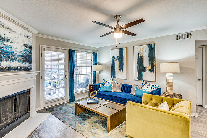 Chic and inviting living room with vibrant decor, featuring a plush blue sofa, modern artwork, and a cozy fireplace.