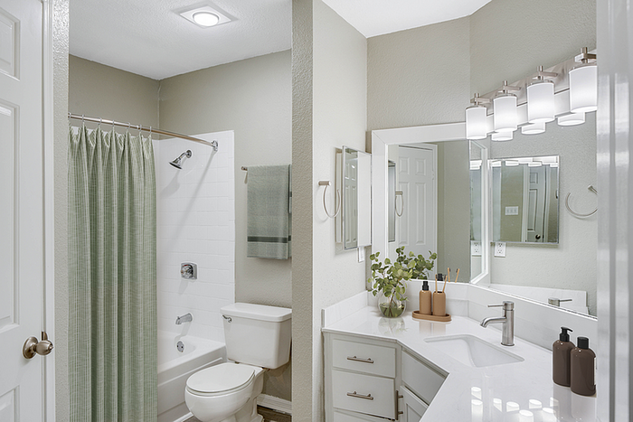 Modern bathroom featuring sleek white countertops, elegant fixtures, and a soothing beige color scheme.