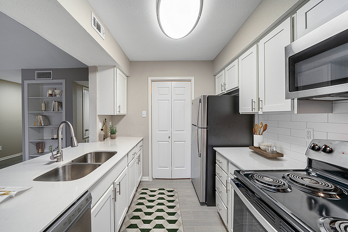 Modern kitchen featuring sleek stainless steel appliances, elegant white cabinetry, and a stylish geometric patterned floor. Perfect for culinary enthusiasts.