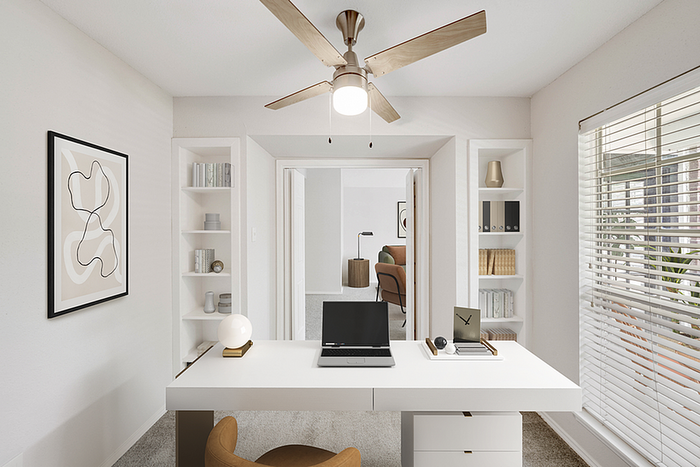Modern home office with sleek white desk, stylish decor, and natural light streaming through window blinds.