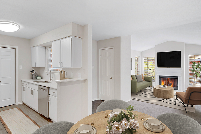 Modern open-plan living area featuring a sleek kitchen, cozy fireplace with mounted TV, and inviting dining space with elegant table decor.