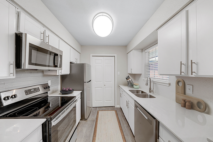 Modern kitchen with sleek stainless steel appliances, white cabinetry, and ample counter space, ideal for culinary enthusiasts.