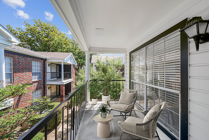 Charming balcony with cozy seating offers a serene outdoor escape overlooking a beautifully landscaped courtyard.