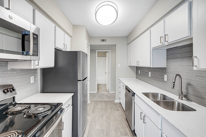 Modern kitchen with sleek stainless steel appliances, white cabinetry, and elegant gray tile backsplash.