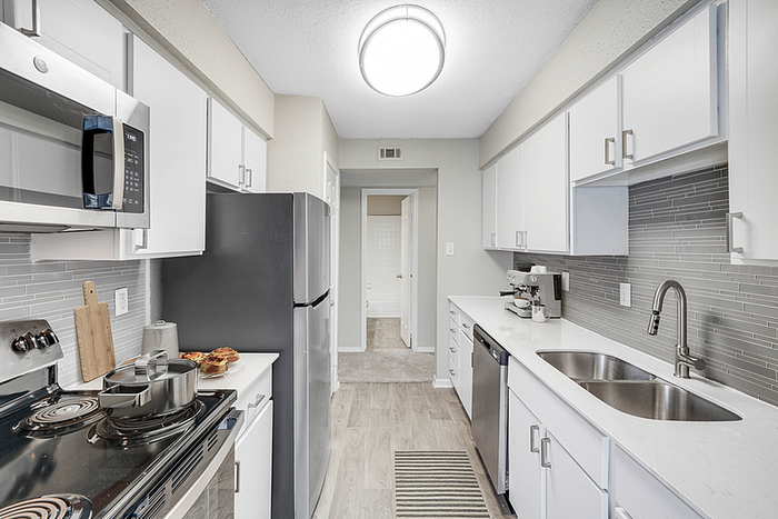 Modern kitchen with sleek stainless steel appliances, pristine white cabinetry, and elegant gray backsplash perfect for culinary enthusiasts.