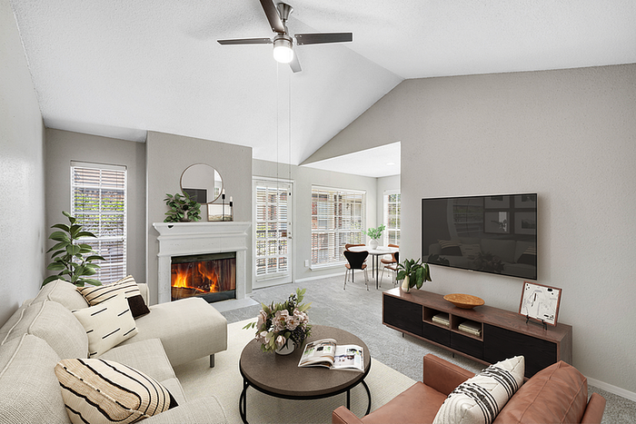 Elegant living room with cozy fireplace, plush sofa, and TV, extending to a bright dining area with abundant natural light.