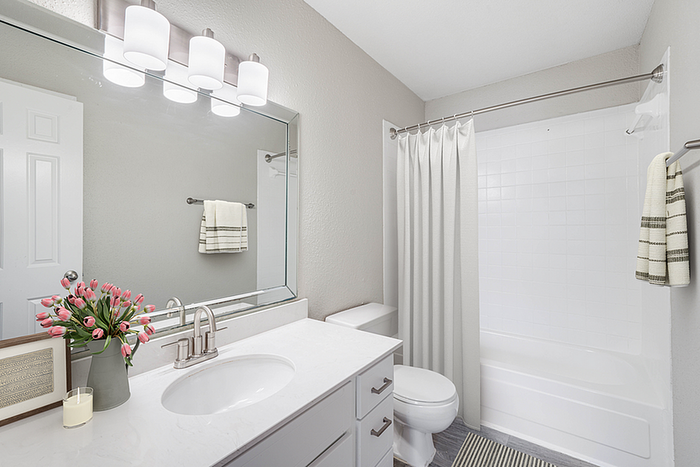 Elegant bathroom featuring a modern vanity with sleek fixtures, soft lighting, and fresh tulips adding a touch of color.