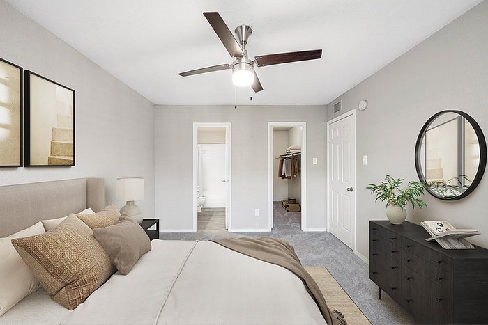 Inviting bedroom with elegant neutral décor, featuring a cozy bed, modern ceiling fan, and chic dresser with stylish mirror.