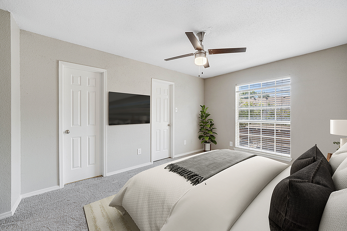 Bright and airy bedroom featuring elegant decor, large window with a scenic view, modern ceiling fan, and a mounted flat-screen TV.