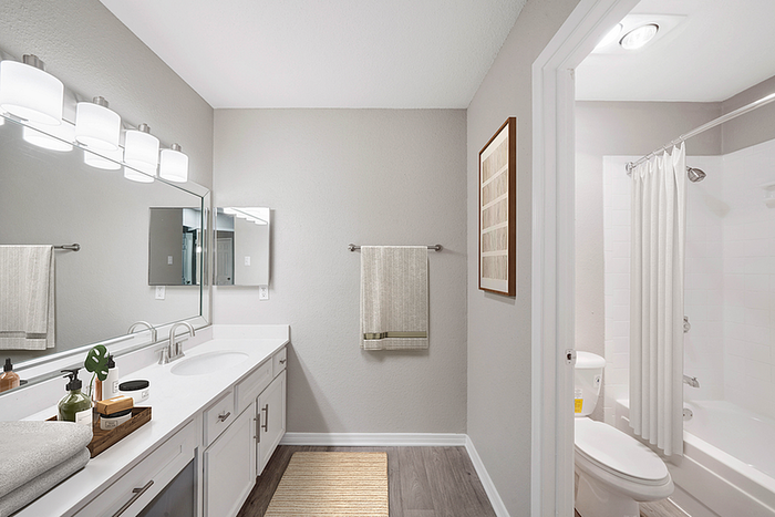Modern bathroom design featuring sleek double sinks, elegant lighting, and a pristine bathtub with a shower curtain.