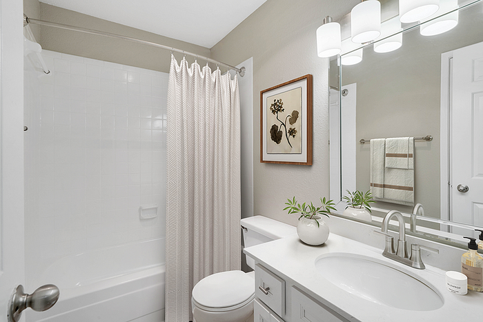 Bright and modern bathroom with elegant fixtures, large mirror, and charming decor plants.