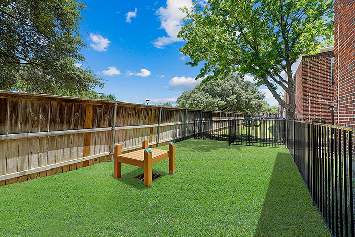 Lush green dog park with secure fencing, perfect for relaxation and outdoor activities, featuring vibrant trees and open skies.