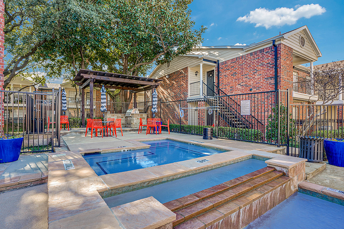 Inviting outdoor pool area with vibrant red seating and lush greenery, ideal for relaxation and social gatherings.