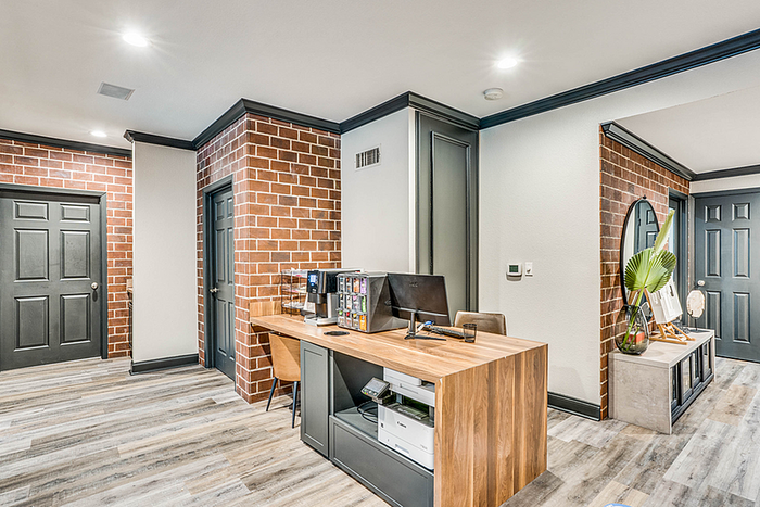 Modern leasing office space with exposed brick walls, sleek wooden desk, and contemporary decor, perfect for a dynamic work environment.