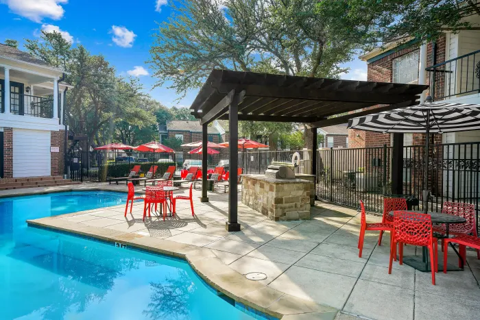 Inviting outdoor pool area featuring vibrant red seating and elegant pergola, perfect for relaxation and entertainment.