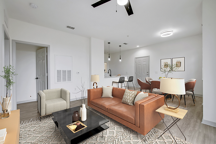 Contemporary open-plan living room with sleek brown leather sofa, stylish armchair, and modern kitchen island in the background, offering a welcoming and spacious ambience.