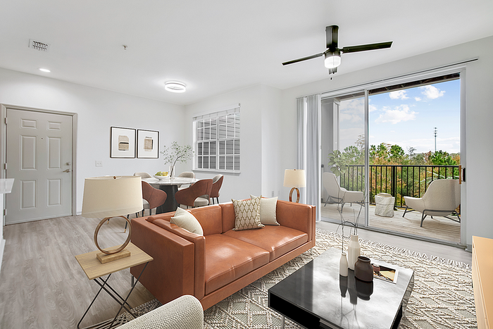 Bright and modern living room with stylish decor, featuring a comfortable leather sofa, elegant dining area, and inviting balcony with lush views.