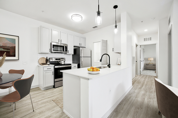 Bright and modern kitchen with sleek white cabinets, stainless steel appliances, and elegant dining area showcasing contemporary artwork.