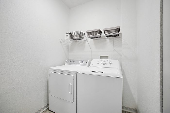 Bright laundry room with modern washer and dryer, featuring organized shelving for efficient storage.
