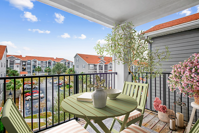 Charming balcony with a cozy seating area, lush greenery, and a vibrant view of stylish apartment buildings.