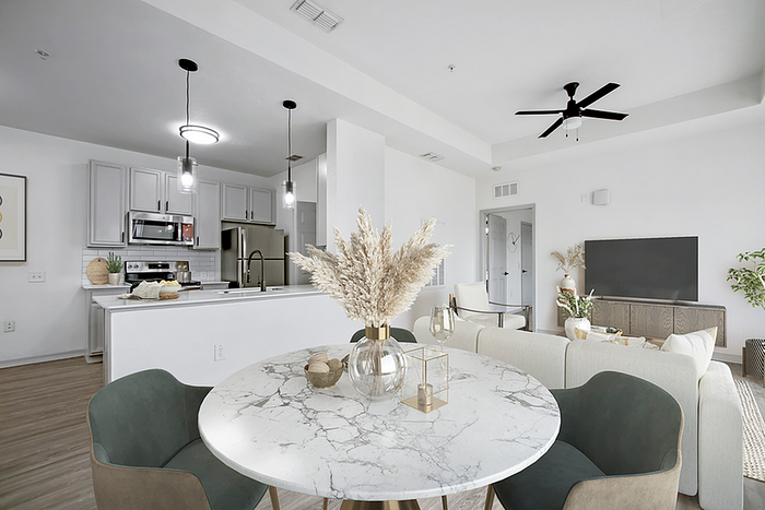 Modern open-plan living area featuring a chic kitchen with stainless steel appliances, elegant dining setup, and a comfortable lounge space with stylish decor.
