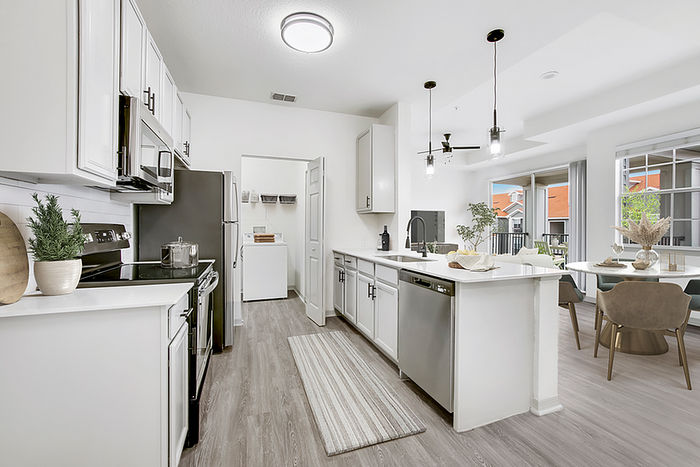 Modern open-concept kitchen and dining area featuring sleek appliances, elegant pendant lighting, and inviting balcony access.