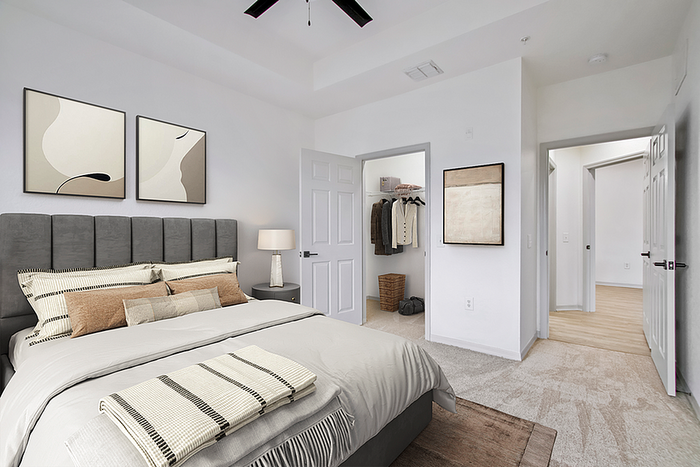 Elegant bedroom with plush bedding, modern decor, and spacious walk-in closet in a luxurious apartment.