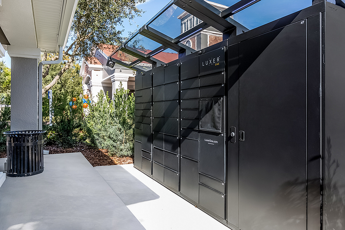 Modern outdoor package lockers at a stylish residential community, surrounded by lush greenery and contemporary architecture.