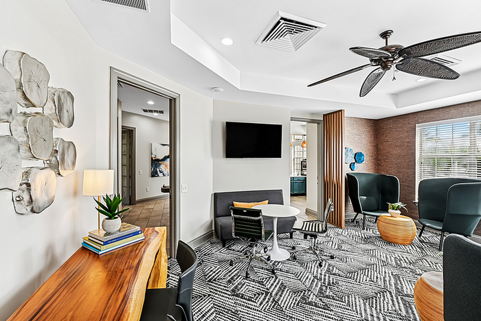Modern and cozy clubhouse lounge featuring stylish furniture, wall art, and large windows offering natural light.