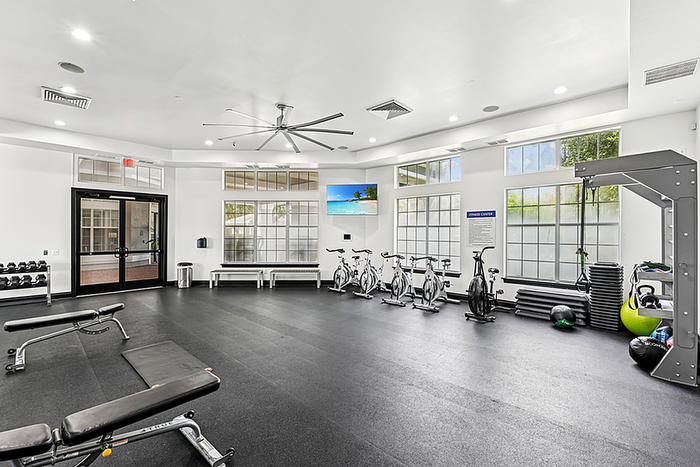 Modern fitness center featuring state-of-the-art exercise bikes, weightlifting equipment, and stylish lighting in a spacious and bright setting.