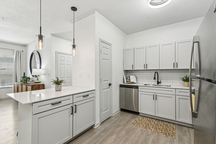 Modern kitchen with sleek white cabinetry, stainless steel appliances, and elegant pendant lighting in a bright and open layout.