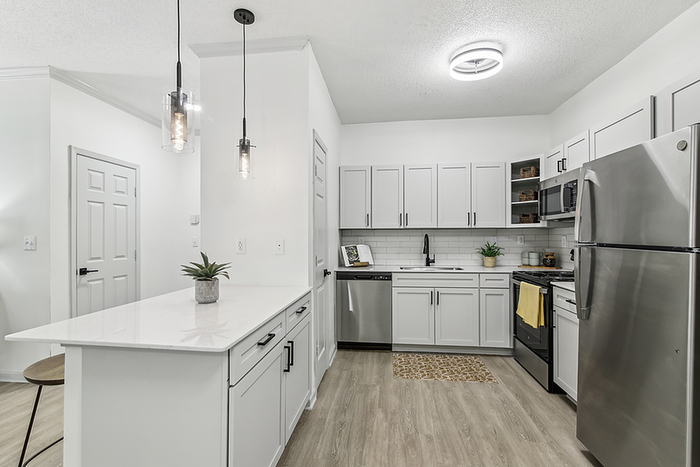 Modern kitchen with sleek white cabinetry, stainless steel appliances, and elegant pendant lighting creating a stylish and functional space.