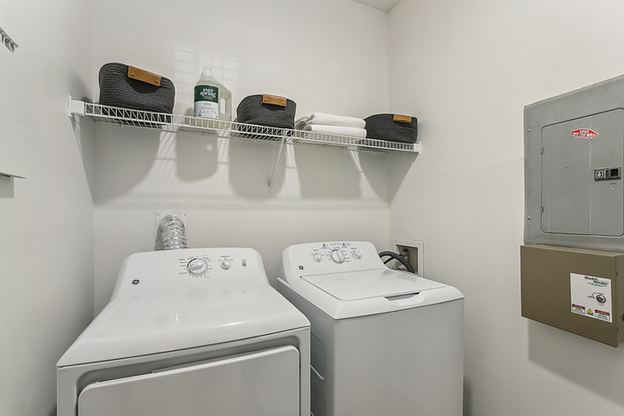 Contemporary laundry room with a sleek washer and dryer set, ample shelf space, and stylish storage baskets.