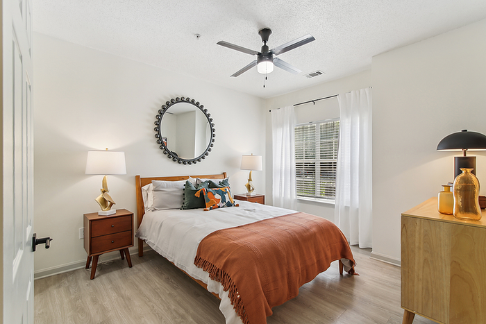 Bright and inviting bedroom with modern wooden furniture, stylish decor, and natural light streaming through large windows.