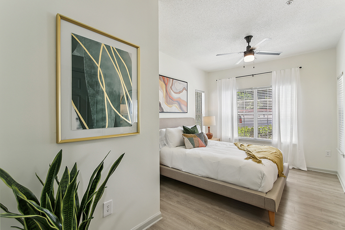 Bright and modern bedroom with elegant decor, featuring a plush bed, stylish artwork, and large windows for natural light.