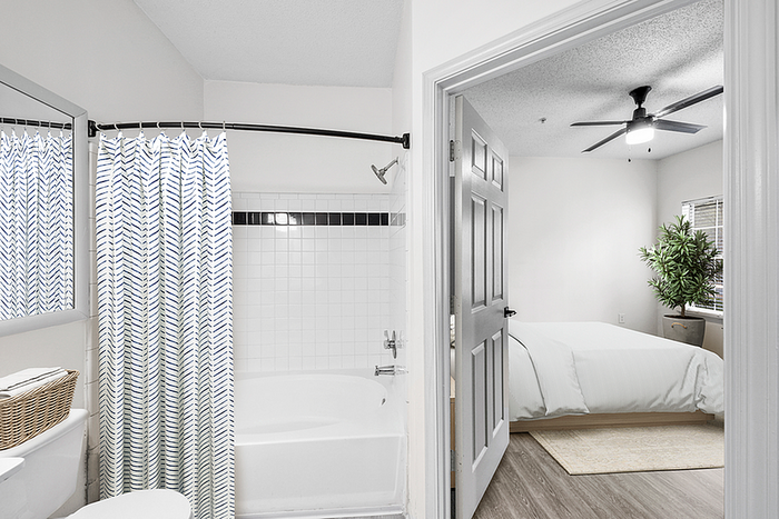 Bright and inviting view of a modern bathroom leading to a cozy bedroom with stylish decor and ample natural light.