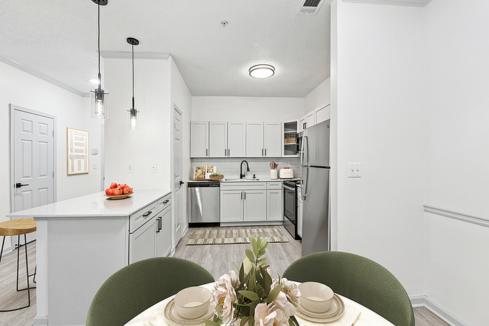 Modern kitchen and dining area with sleek white cabinetry, stainless steel appliances, and elegant pendant lighting. A cozy nook with stylish decor for intimate gatherings.