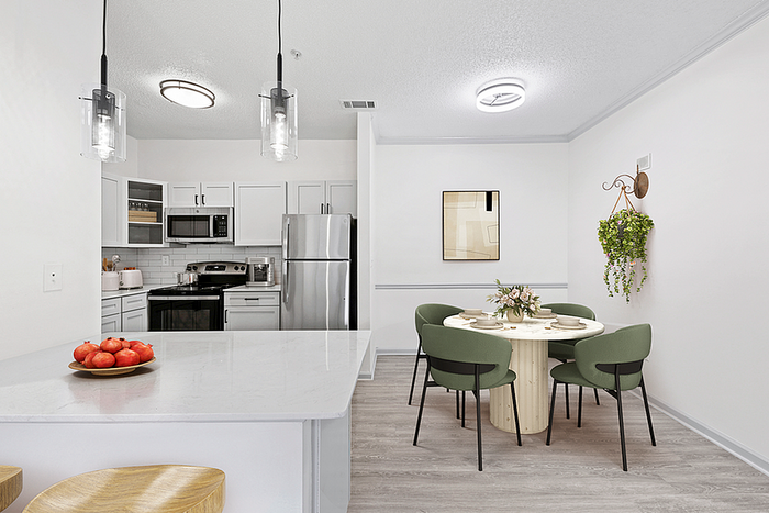 Contemporary kitchen and dining area with modern stainless steel appliances, elegant lighting, and a cozy round dining table for stylish living.