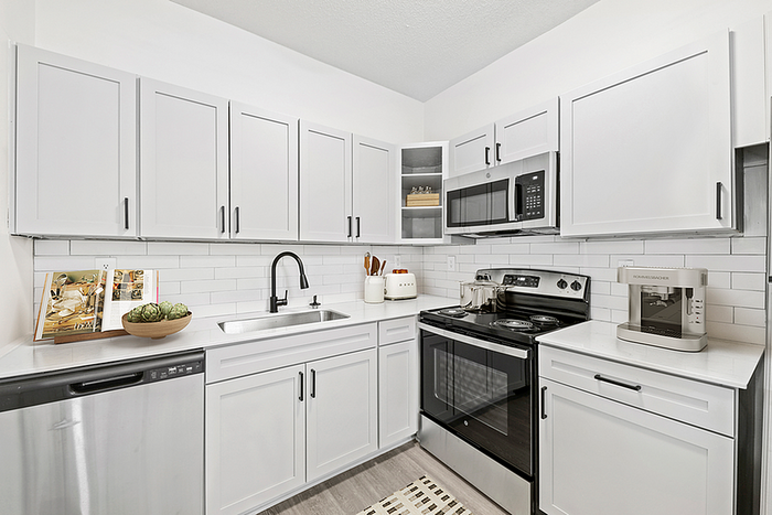 Modern kitchen with sleek white cabinetry, stainless steel appliances, and elegant tiled backsplash.