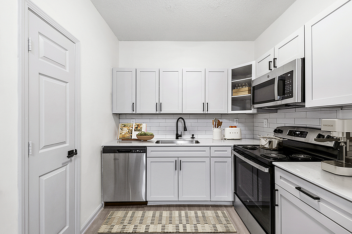 Modern kitchen featuring sleek white cabinetry, stainless steel appliances, and a stylish subway tile backsplash.