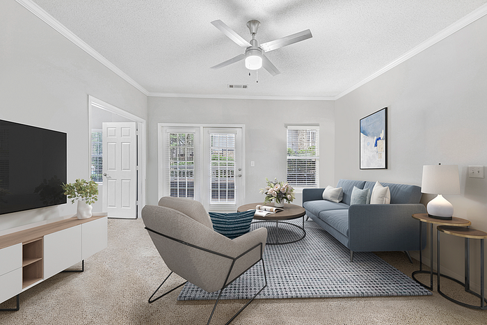 Inviting living room with modern decor, featuring a chic blue sofa, stylish armchair, and elegant coffee table, complemented by natural light streaming through large windows.
