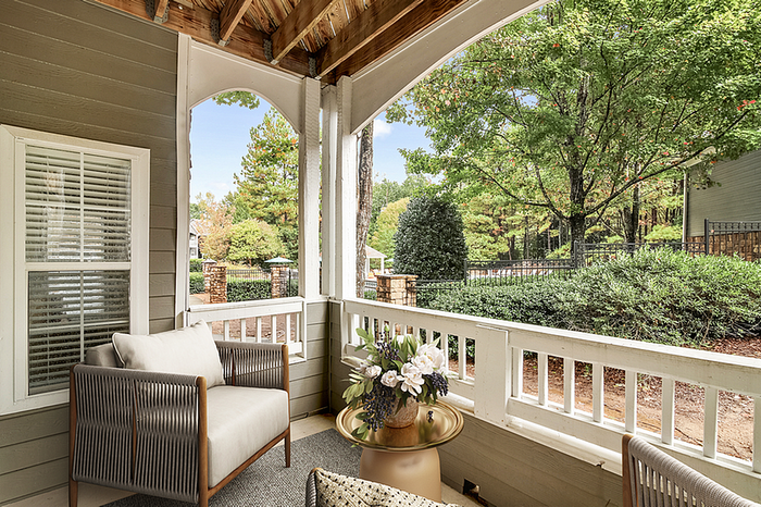 Charming outdoor patio with cozy seating overlooking lush greenery and vibrant trees, perfect for relaxing and enjoying nature.