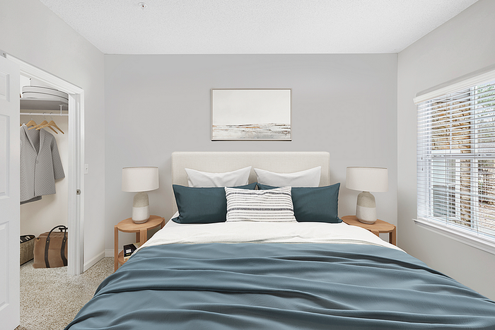 Bright and inviting bedroom with a cozy bed, elegant nightstands, and ample closet space, enhanced by natural light from a large window.