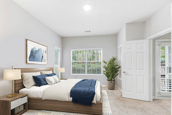 Bright and airy bedroom featuring a modern wooden bed, stylish decor, and large windows overlooking lush greenery.