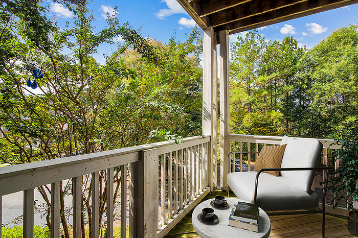 Inviting balcony retreat with cozy seating, surrounded by lush greenery and a serene atmosphere.