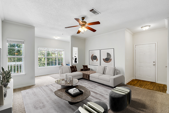 Bright and inviting living room with modern furnishings, large windows offering scenic views, and elegant ceiling fan enhancing comfort.