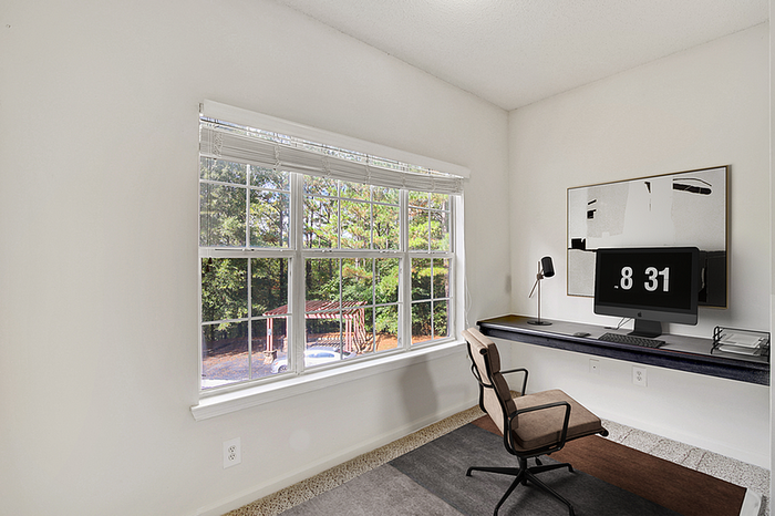 Bright home office with scenic views, featuring a modern desk setup and stylish decor.