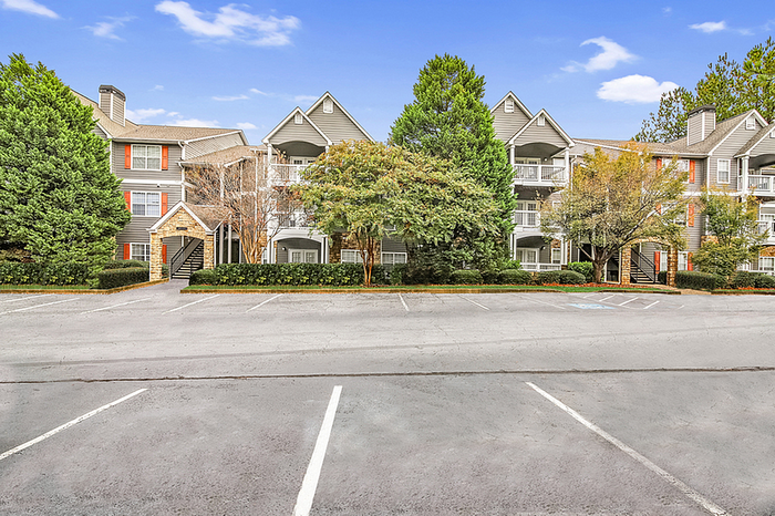 Charming apartment community with elegant architecture, surrounded by lush greenery and ample parking space.